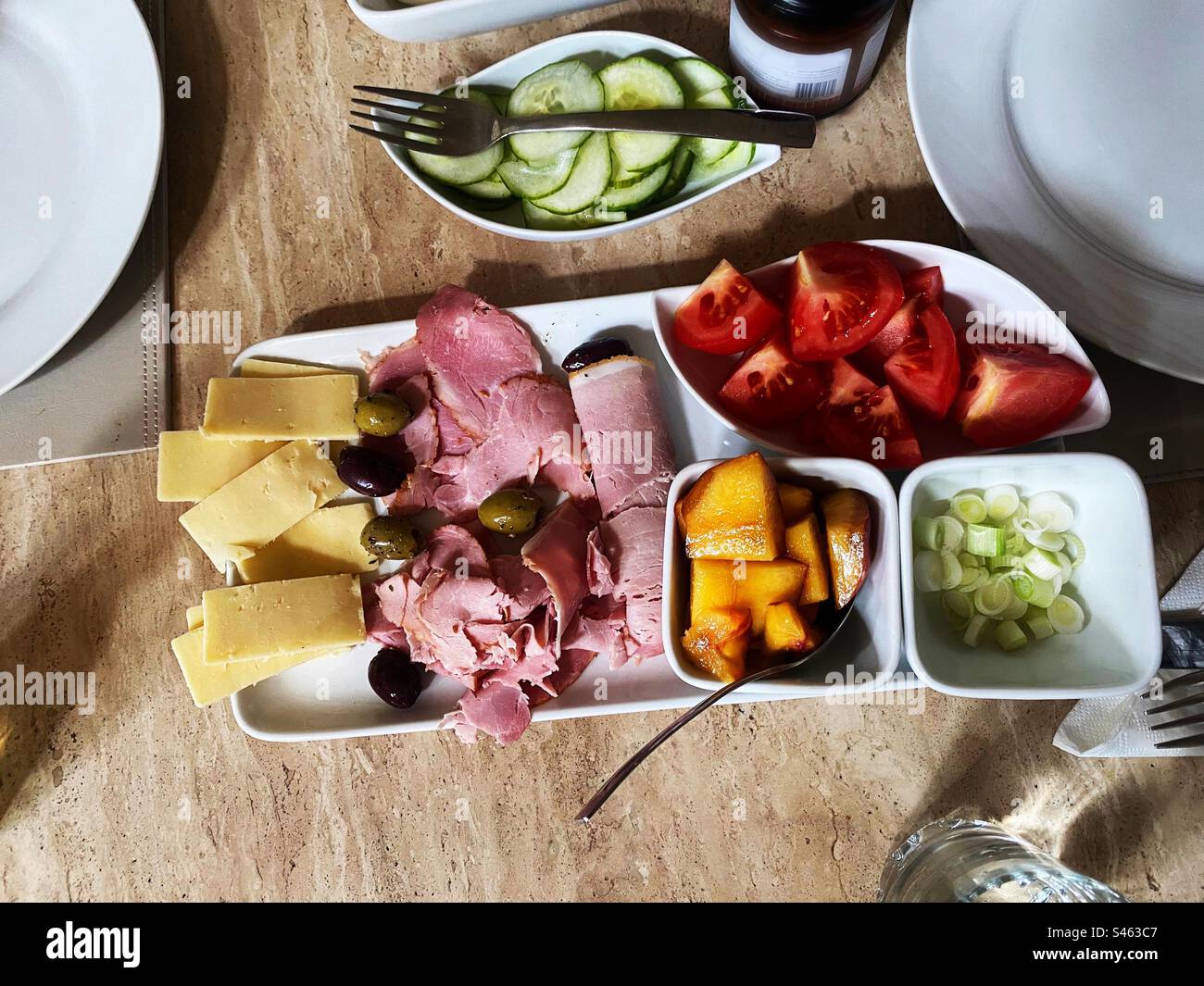 Mittagessen mit gekochtem Schinken, Oliven, Käse, Tomaten, Gurken, Schalotten- und Pfirsichscheiben. - Smartphone-aufgenommenes Stockfoto
