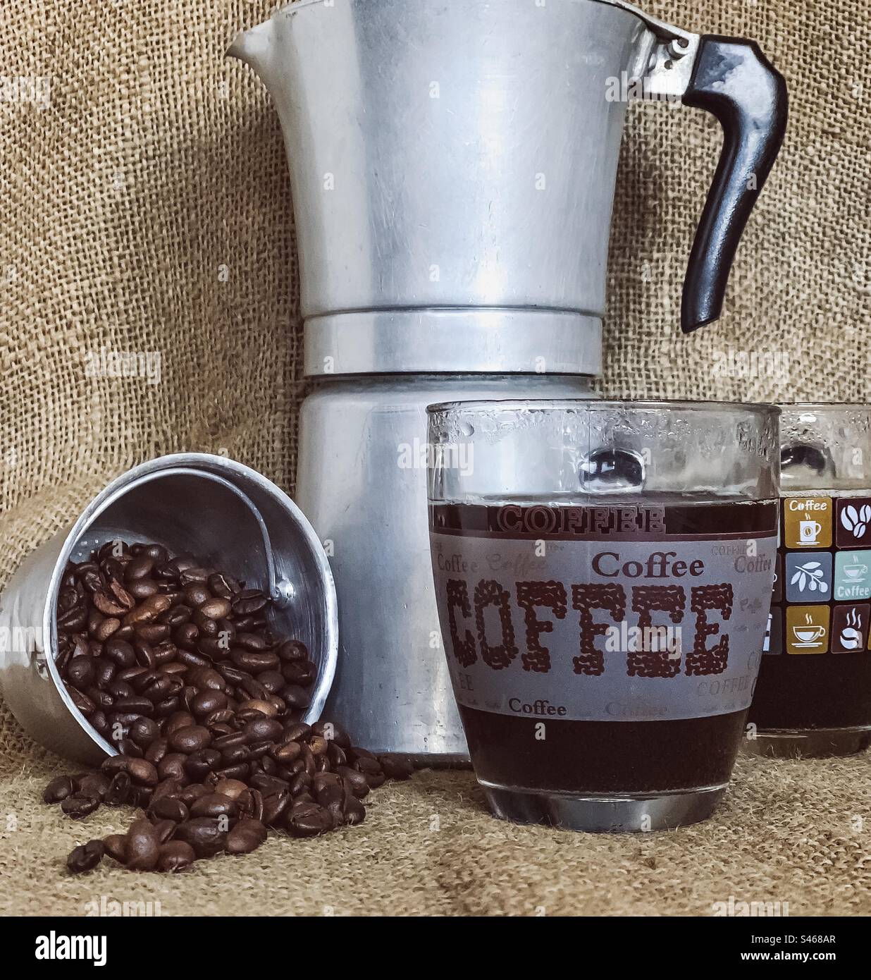 Kaffeebohnen, schwarzer Kaffee und Kochtopf auf Sacktuch - Smartphone-aufgenommenes Stockfoto