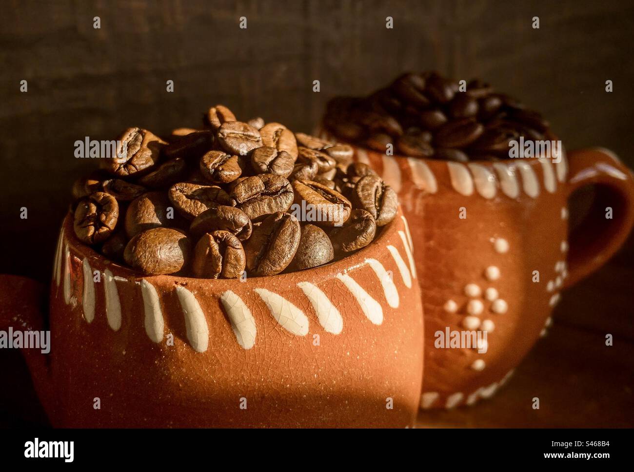 2 Terrakotta-Tassen gefüllt mit Kaffeebohnen - Smartphone-aufgenommenes Stockfoto