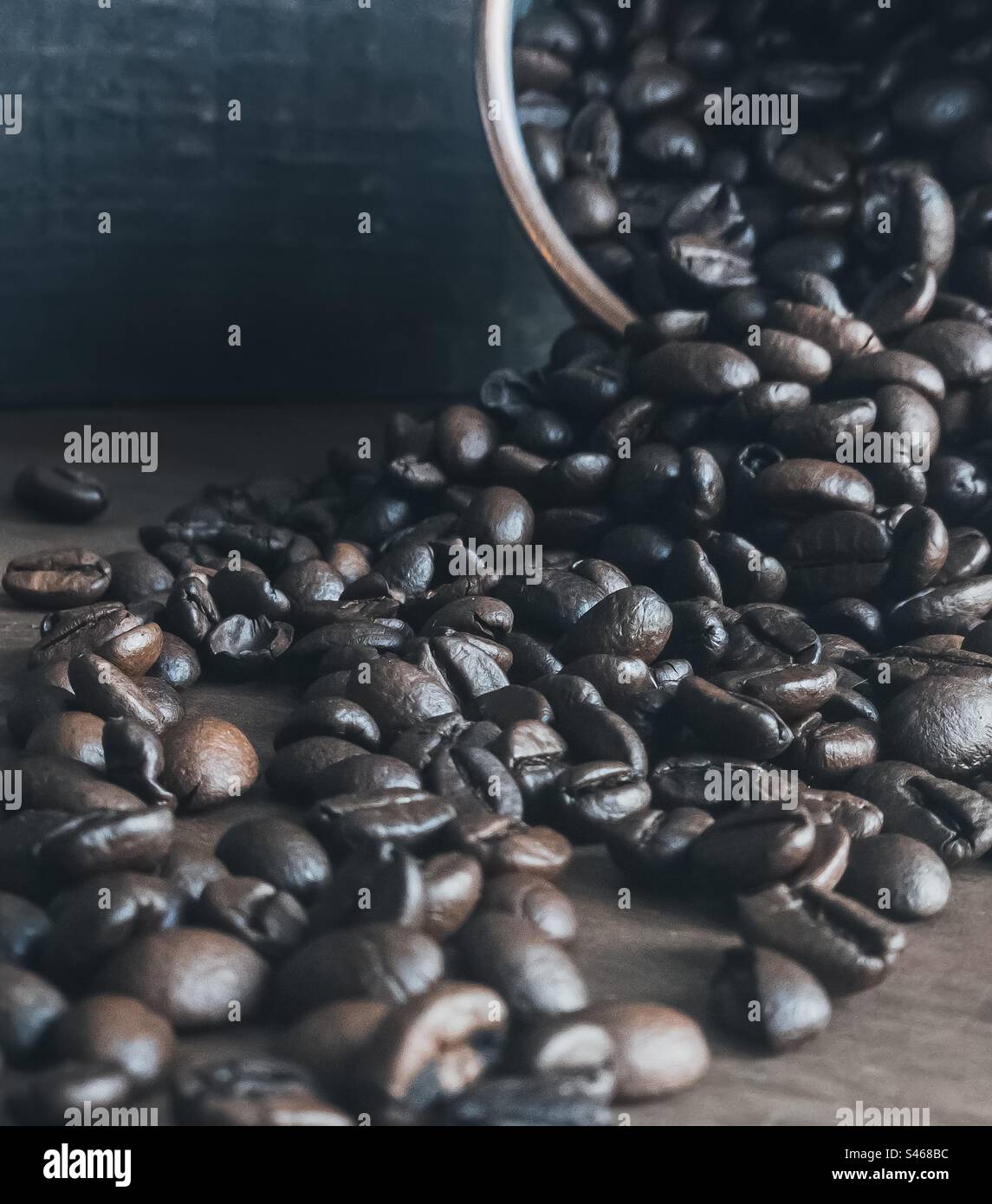 Kaffeebohnen, die aus einem Metallbehälter auslaufen - Smartphone-aufgenommenes Stockfoto