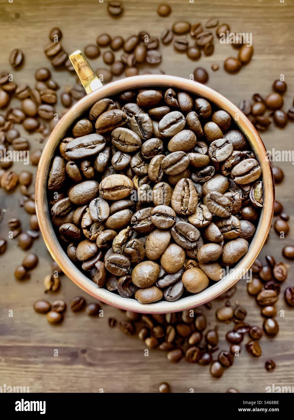 Ein Kupferbecher, von oben gesehen, gefüllt mit Kaffeebohnen - Smartphone-aufgenommenes Stockfoto