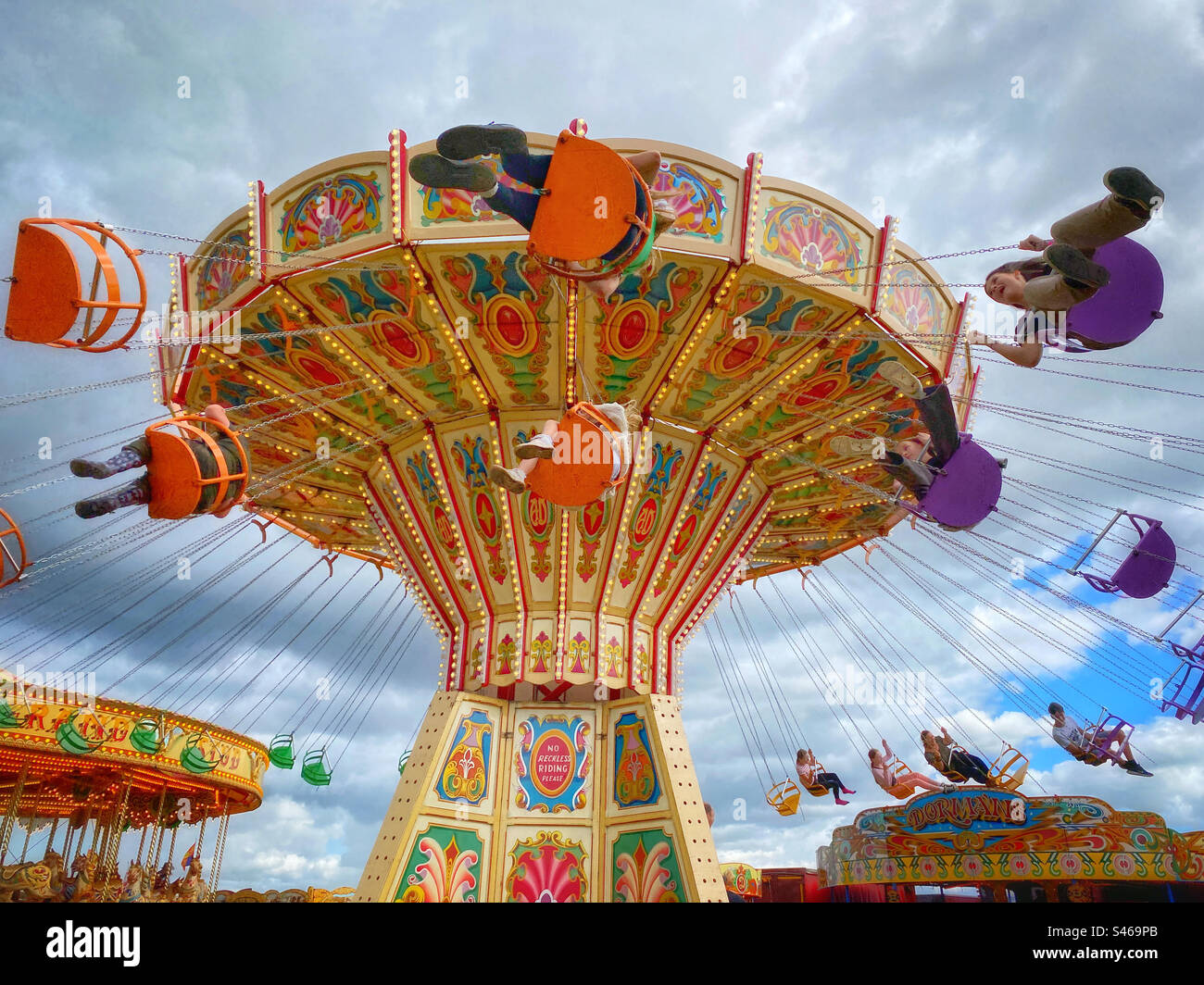 Ich habe Spaß dabei, auf dem Sessel-O-Flugzeug auf einer englischen Landmesse herumzuschaukeln. Kinderunterhaltung während der Sommerschulferien! Foto ©️ COLIN HOSKINS. - Smartphone-aufgenommenes Stockfoto