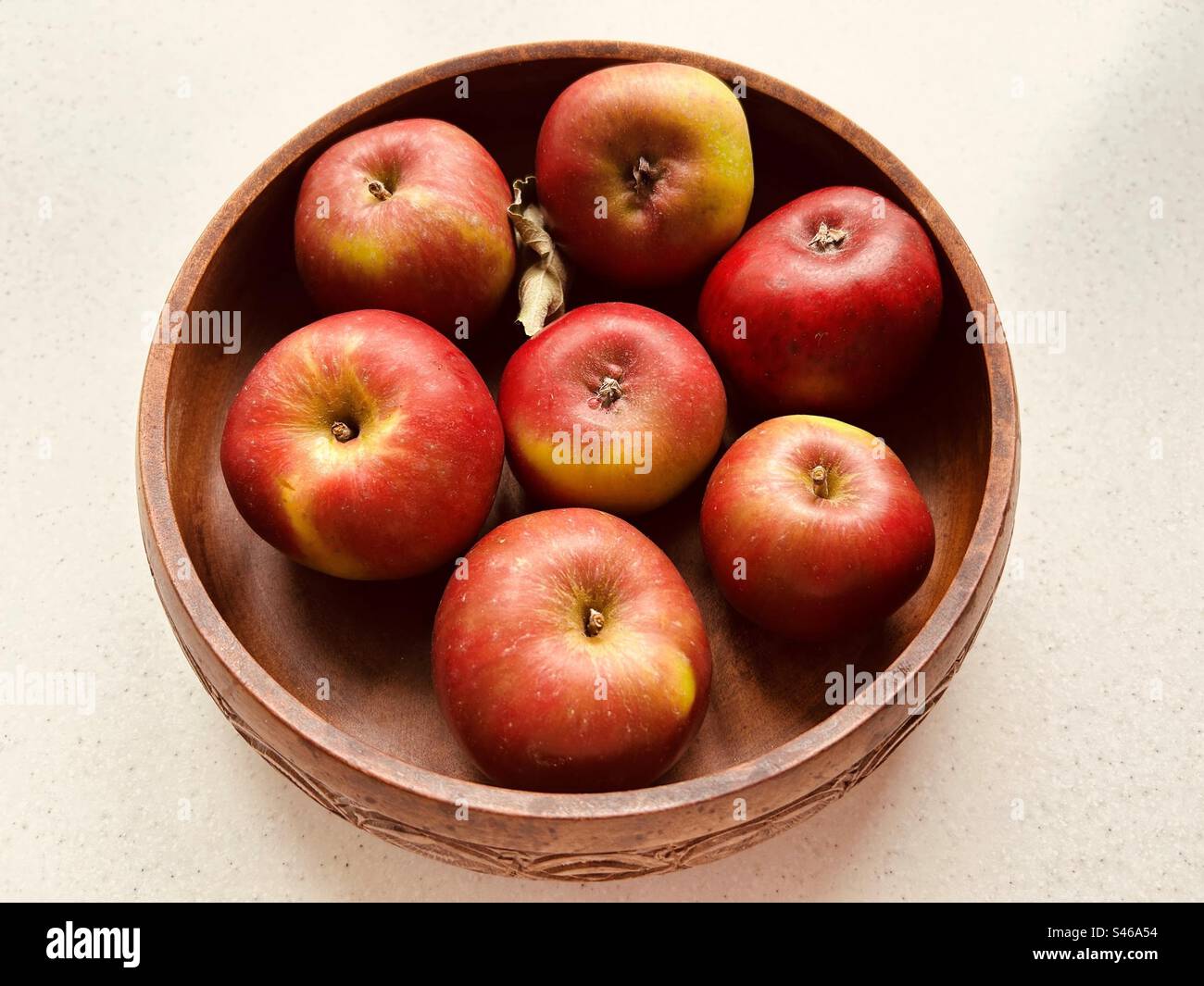 Sieben Äpfel in einer runden Holzschale. Rote und grüne Äpfel. Gestern im Obstgarten der Gemeinde gesäubert. Frisch und saftig. Stockfoto