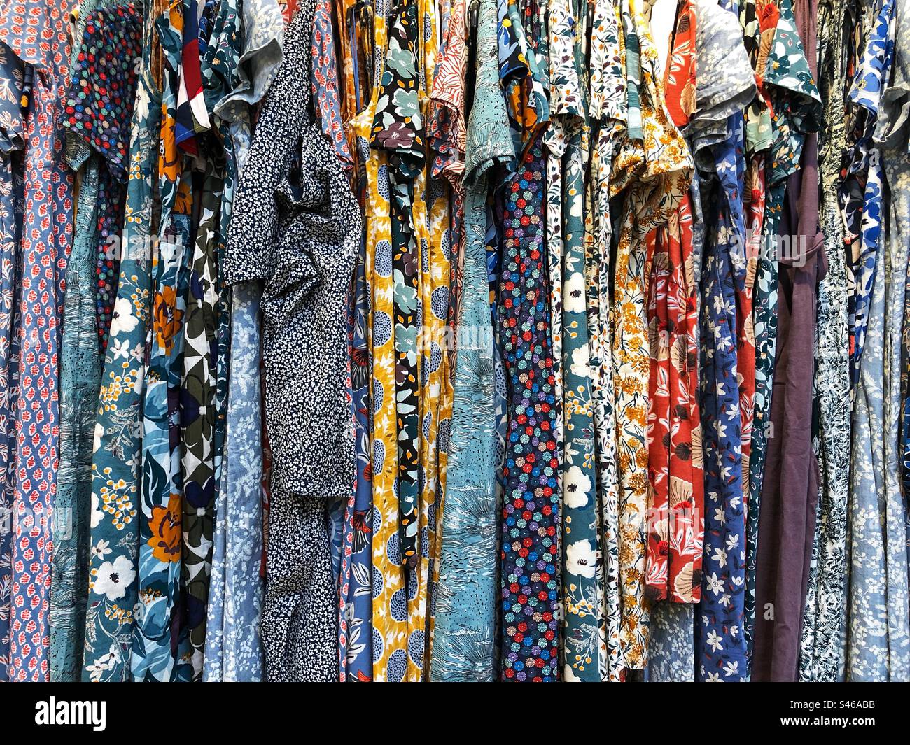 Vollformat-Modehintergrund mit Reihen hübscher Blumenkleider auf dem Verkaufsregal eines Damenbekleidungsgeschäfts mit Kopierbereich Stockfoto