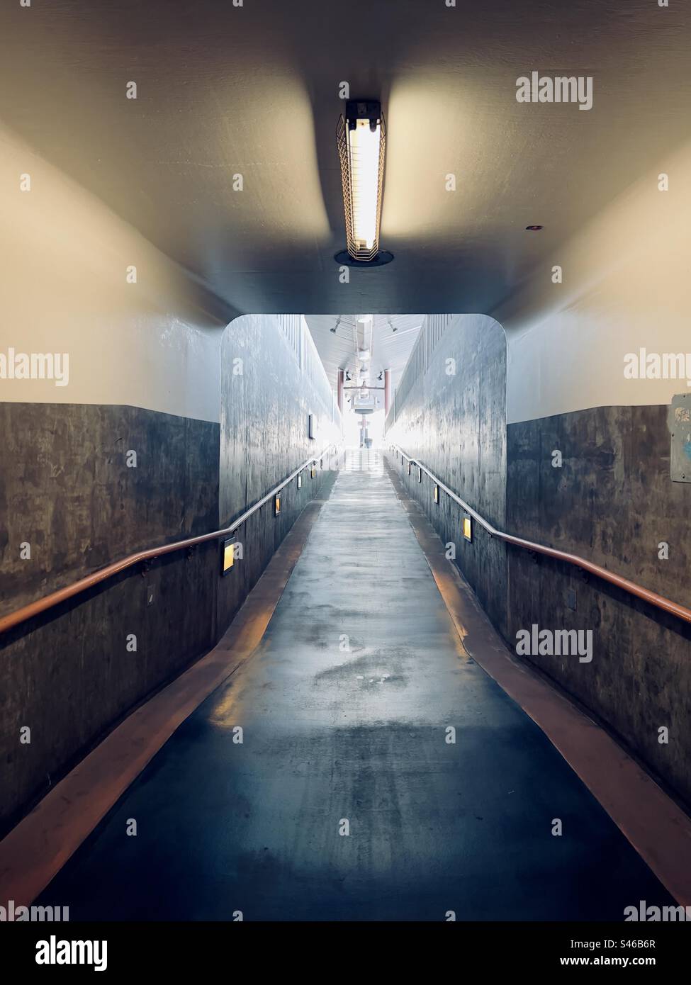 Blick vom dunklen Fußgängertunnel bis zum Tageslicht am Ende der Rampe zum Bahnsteig, Union Station in Downtown Los Angeles Stockfoto