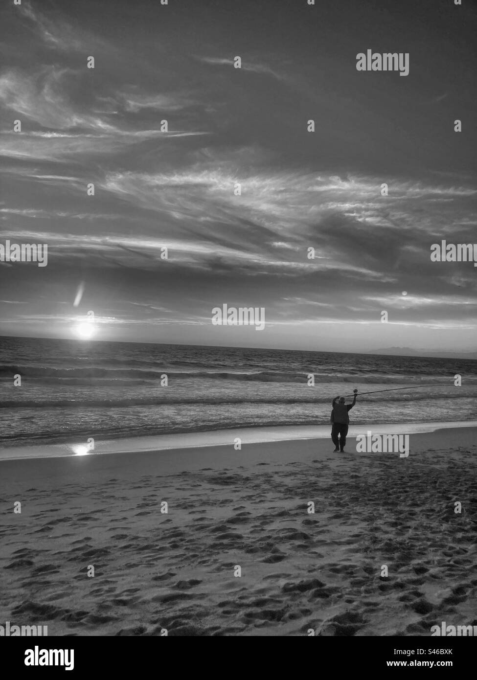 Monochromatisches Bild des Lagoa de Albufeira Strandes mit Fischern bei Sonnenuntergang. Sesimbra/Setubal, südlich von Portugal. Stockfoto