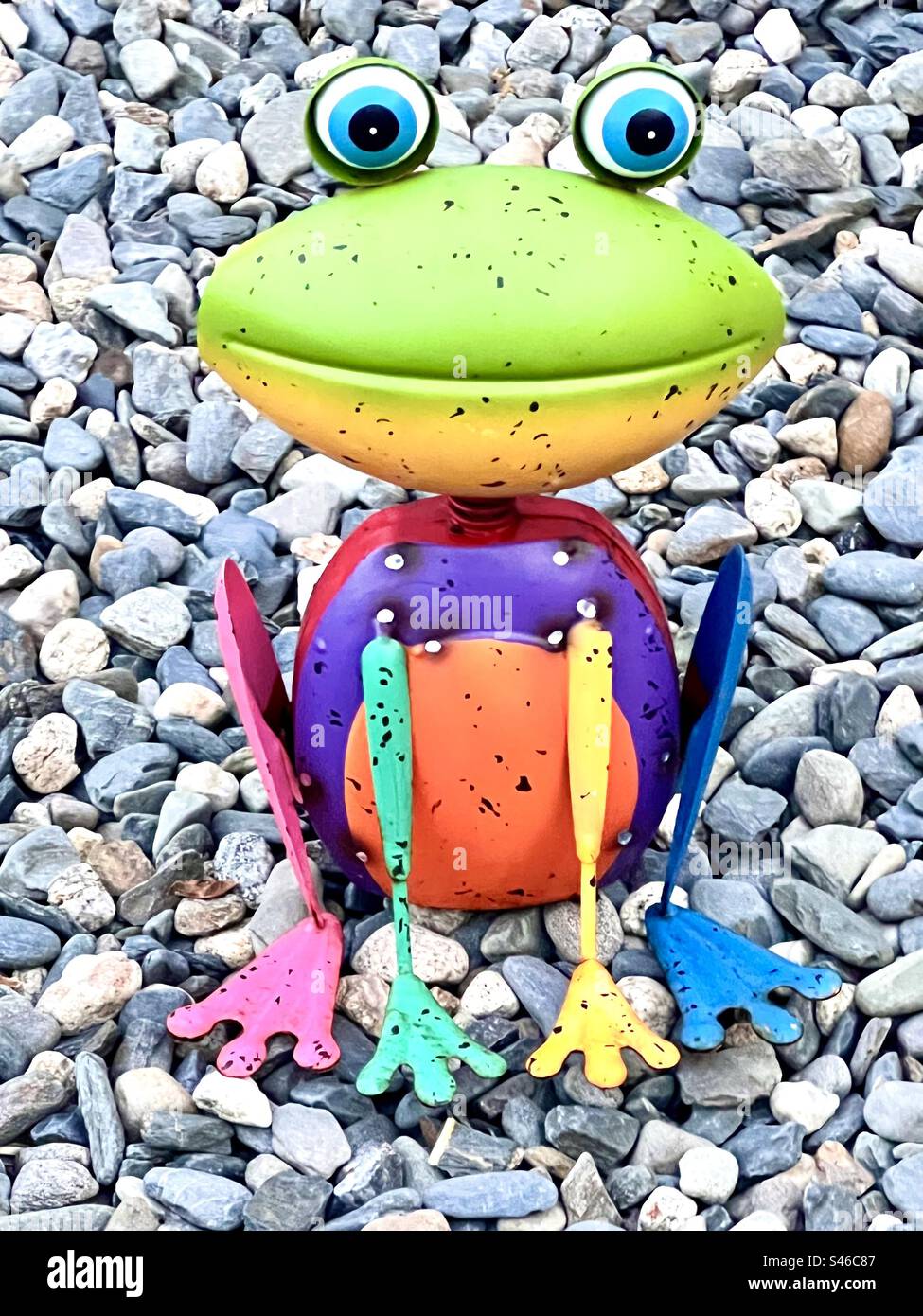 Regenbogenfrosch aus Metall auf Kieselsteinen Stockfoto
