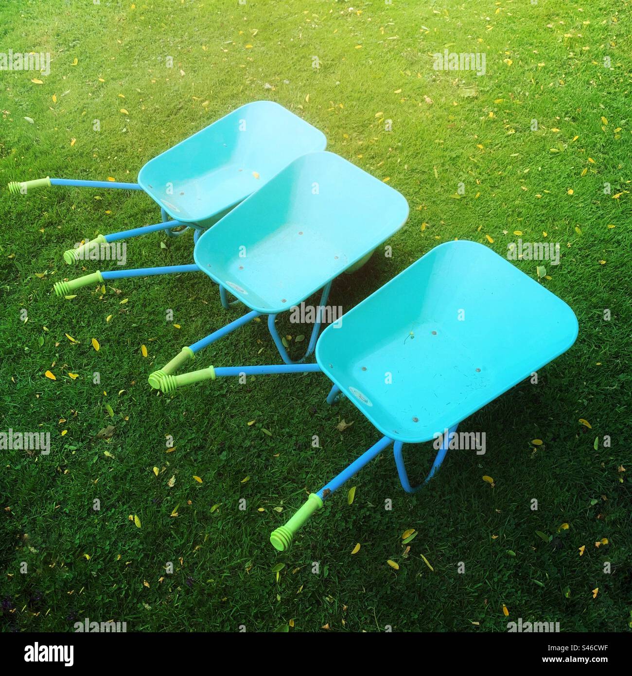 Drei Schubkarren für den Kindergarten auf einem grünen Sommergarten Stockfoto