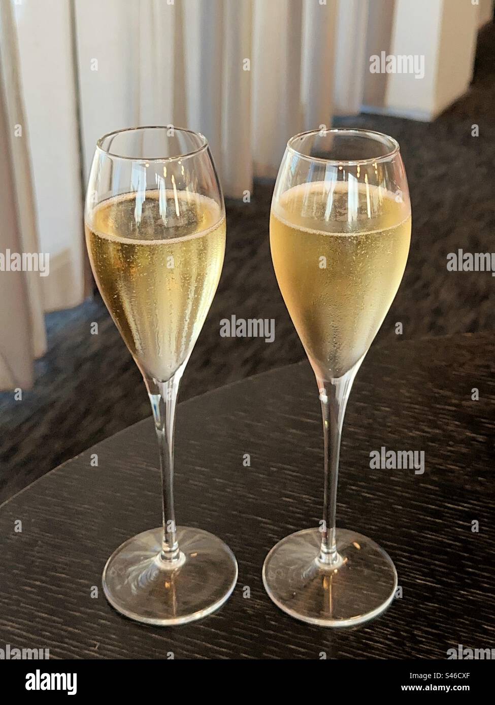 Zwei Flötengläser Champagner auf einem Tisch in einer Hotellounge. Keine Personen. Stockfoto