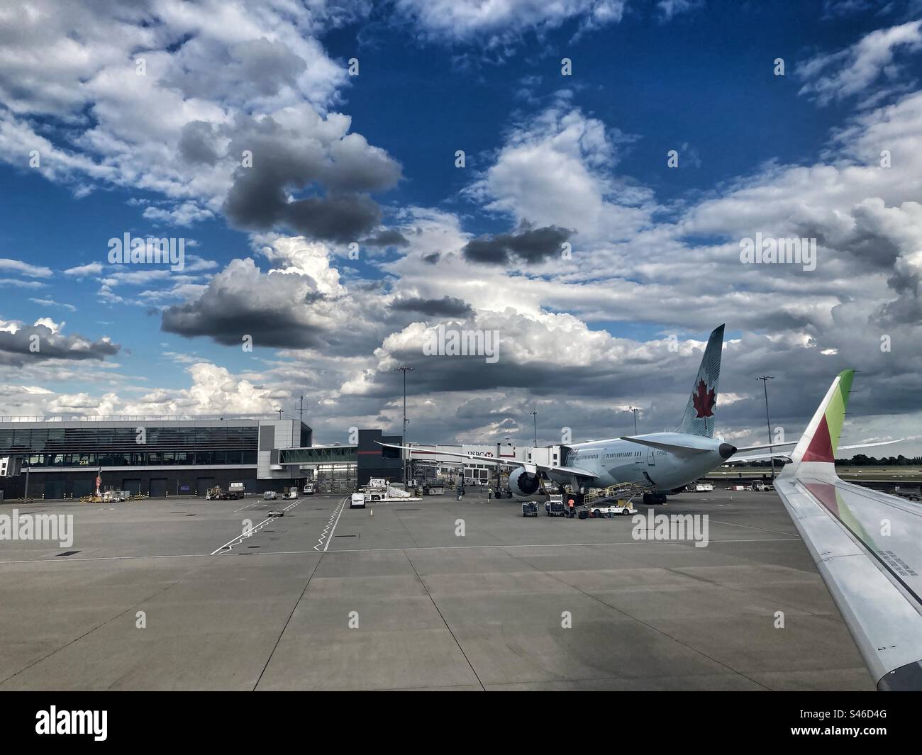 Wolken und Flugzeuge im Flughafen, mit Nahansicht des Flügels mit Tap-Logo. - Smartphone-aufgenommenes Stockfoto