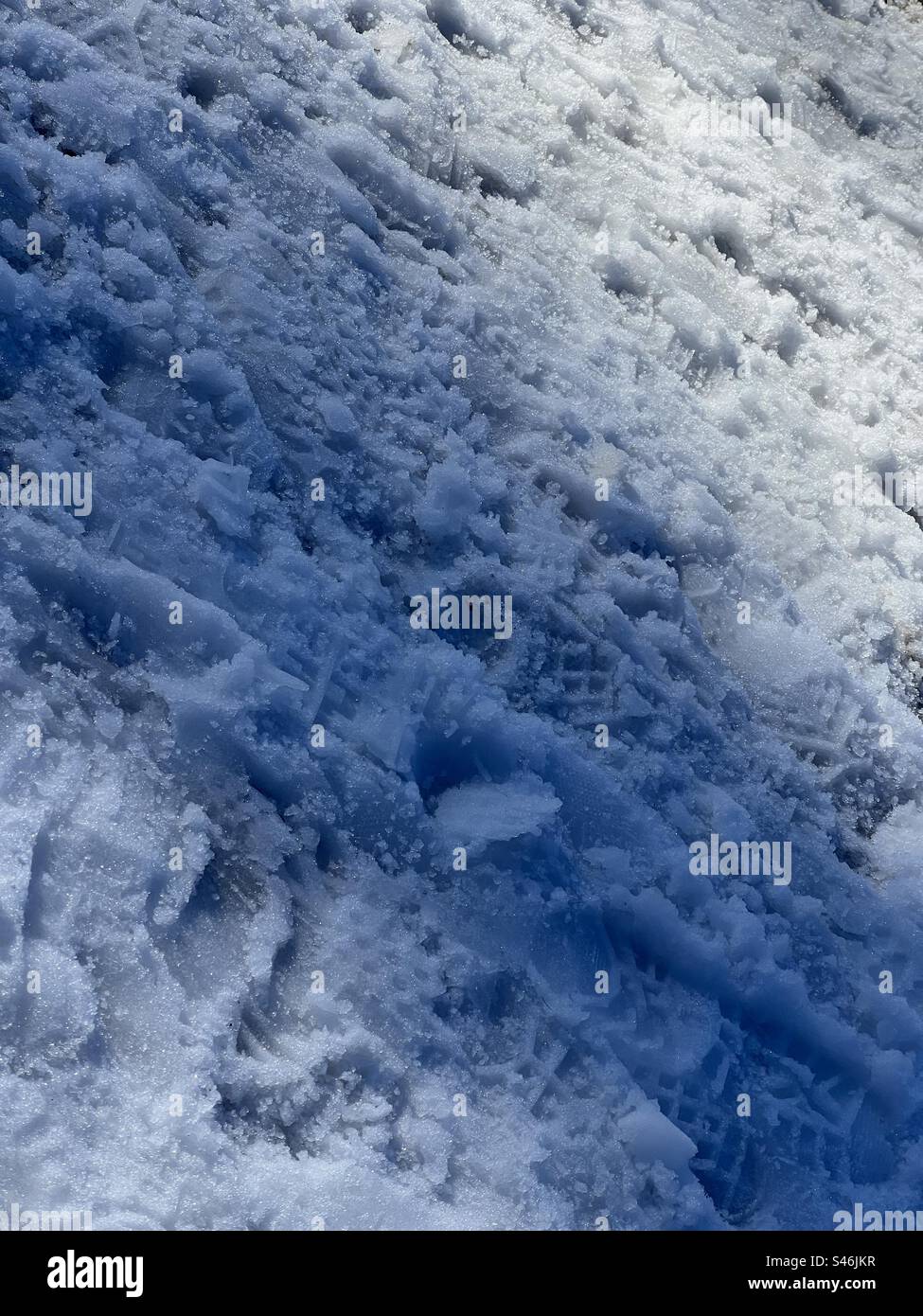 Starke Wintersonne und abstrakte Muster auf Schnee in den kalifornischen Bergen schaffen einen texturierten Winterhintergrund im Porträtformat Stockfoto