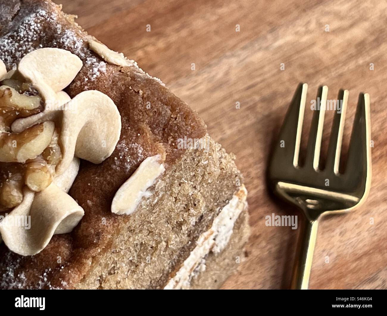Eine Scheibe Kaffeekuchen mit goldener Dessertgabel auf einem Holzbrett Stockfoto
