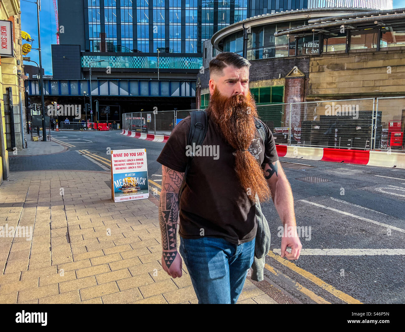 Sehr behaarter Mann mit langem Bart, der durch die Stadt läuft Stockfoto