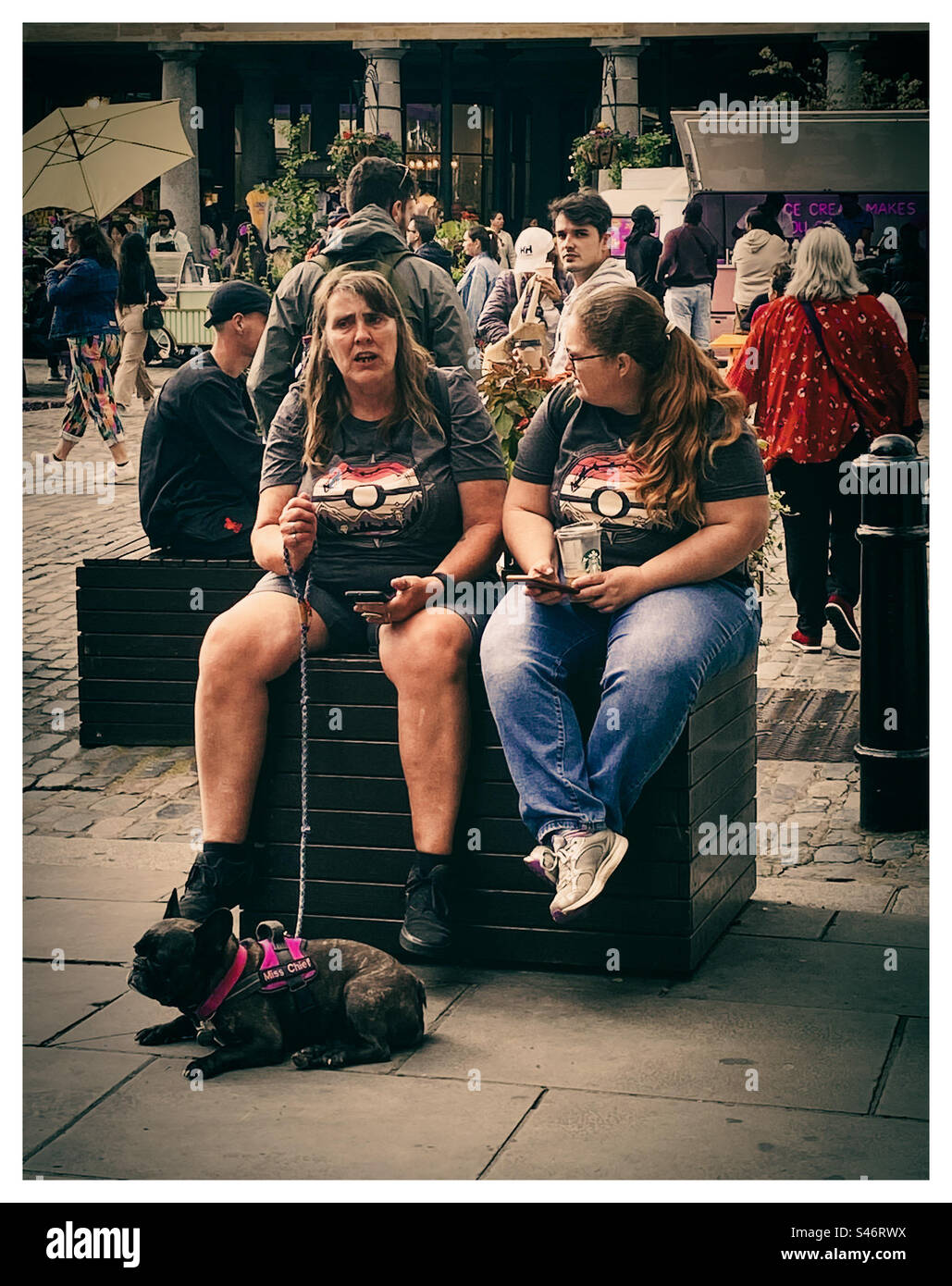 Zwei Frauen in passenden T-Shirts mit einem französischen Bulldog in Covent Garden London England Stockfoto