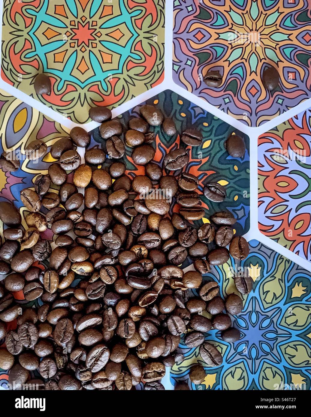 Kaffeebohnen wurden über bunte sechseckige Fliesen geschüttet - Smartphone-aufgenommenes Stockfoto