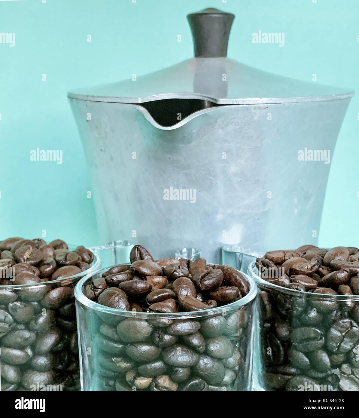 Klare Gläser Kaffeebohnen mit Herdtopf vor türkisfarbenem Hintergrund - Smartphone-aufgenommenes Stockfoto
