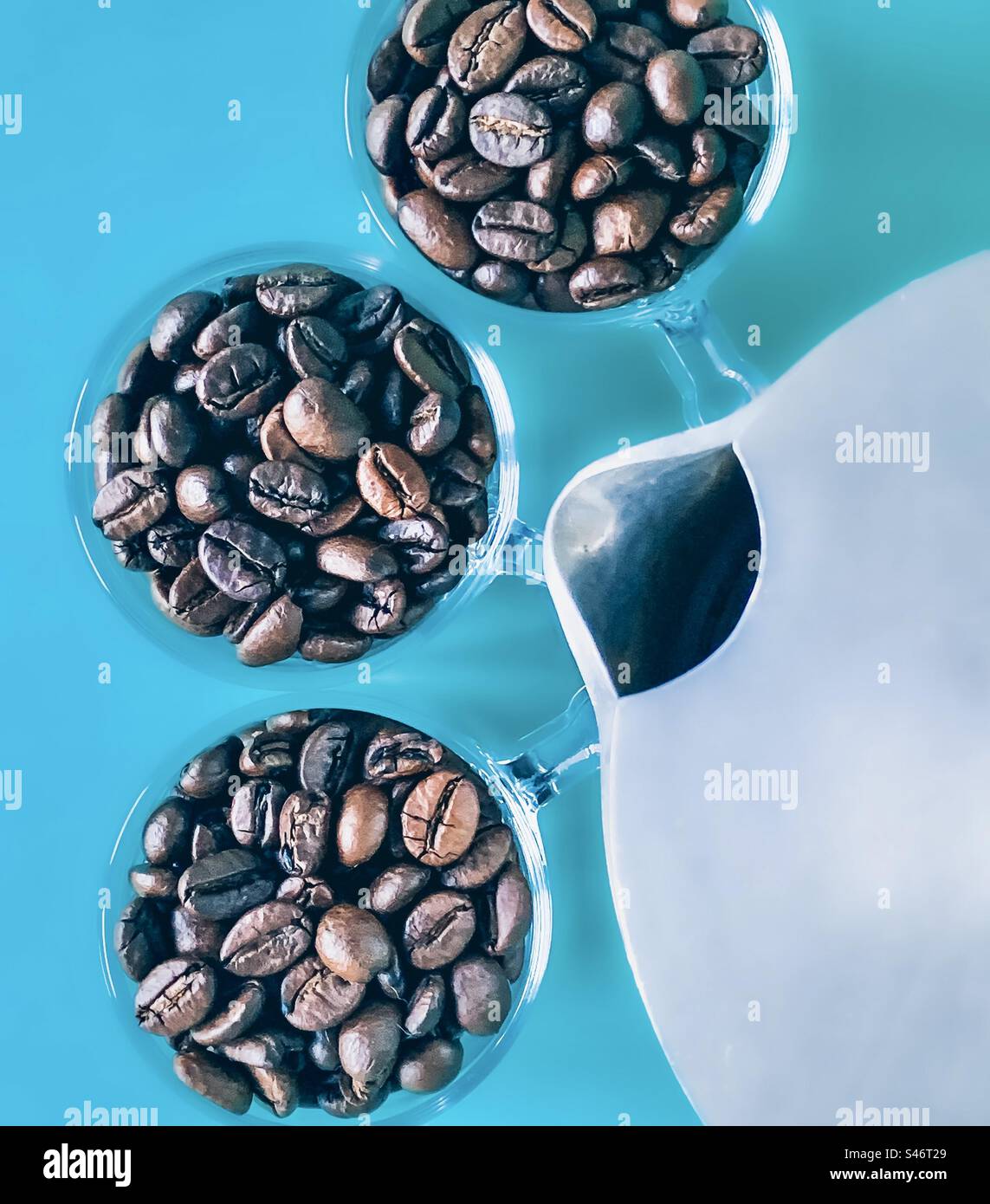 Gläser voller Kaffeebohnen mit flachem Kochfeld lagen auf türkisfarbenem Hintergrund - Smartphone-aufgenommenes Stockfoto