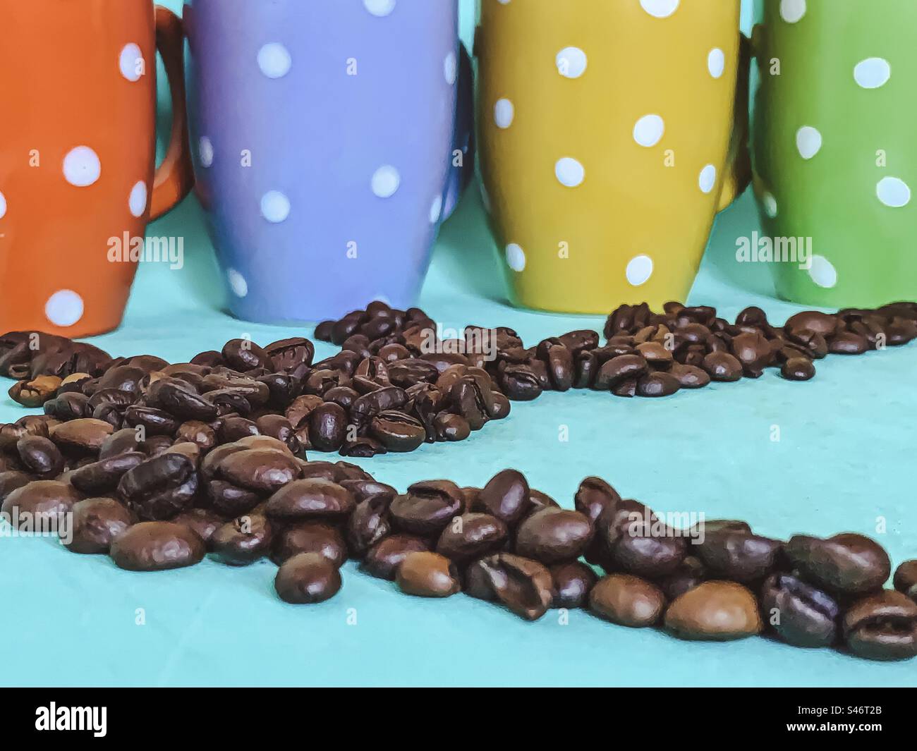 Kaffeebohnen und bunte Tassen mit Punktmuster. - Smartphone-aufgenommenes Stockfoto