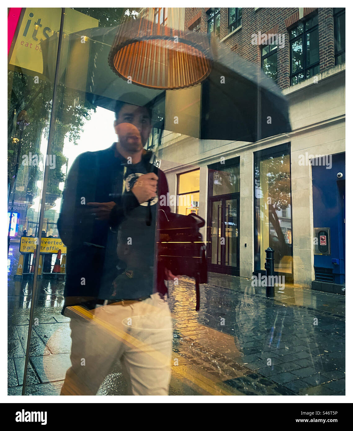 Ein Mann geht mit einem Regenschirm im Regen in London spazieren Stockfoto