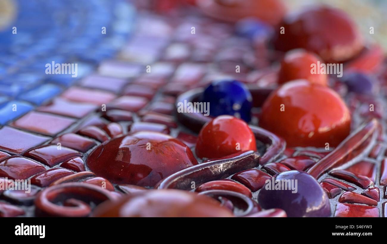 Aus nächster Nähe sehen Sie blaue und rote Keramikformen mit glasierten roten, gelben und blauen Fliesen, die Teil einer Außeninstallation sind und bei bewölktem Licht zu sehen sind. Querformat, flacher Fokus - Smartphone-aufgenommenes Stockfoto
