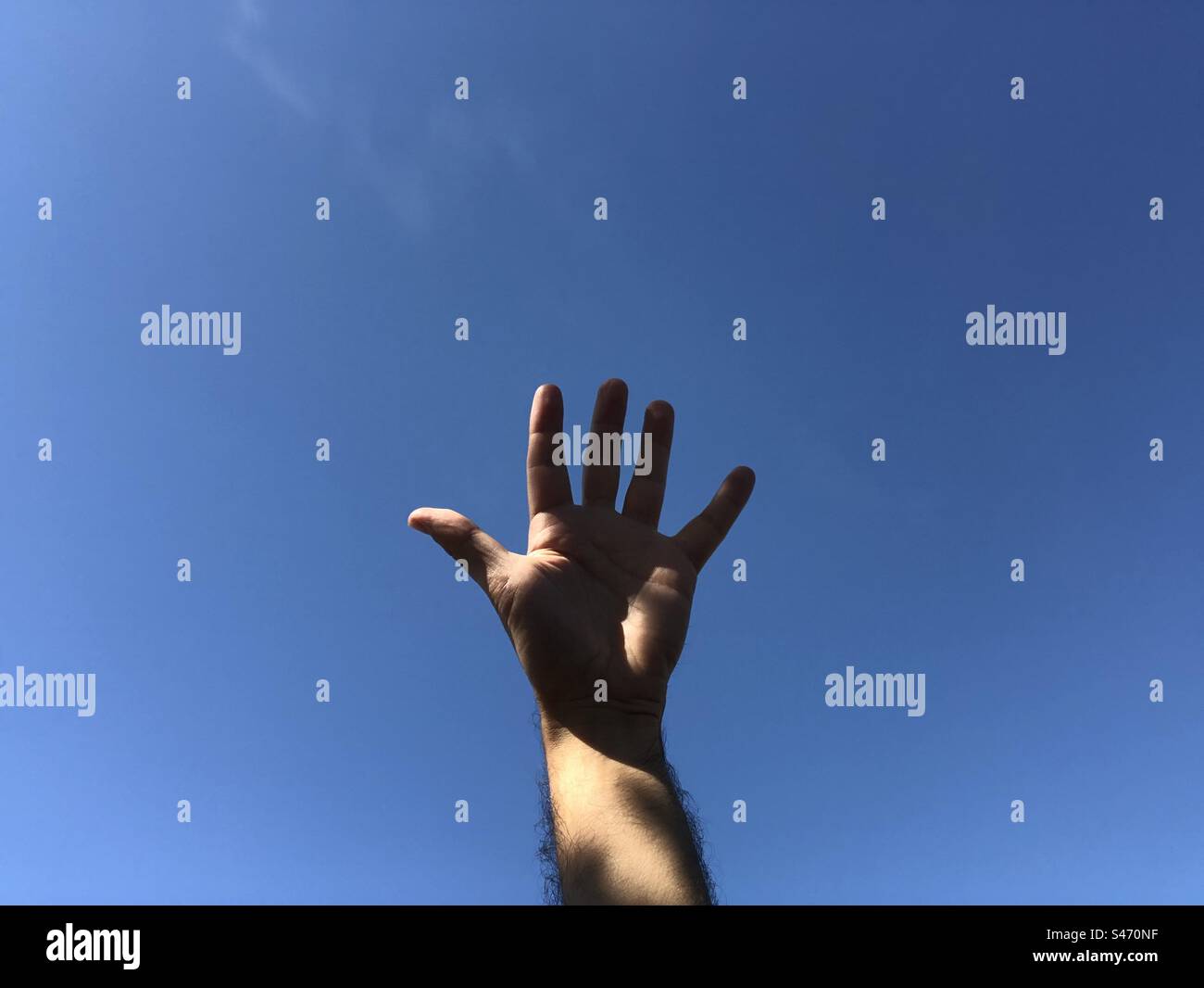 Hand einer Person gegen den blauen Himmel - Smartphone-aufgenommenes Stockfoto