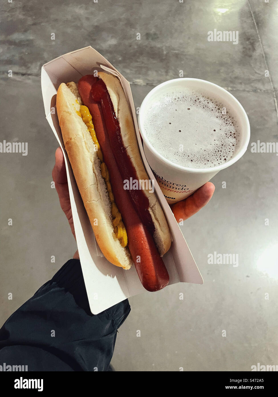 Ein Hot Dog und ein Bier werden bei einer Sportveranstaltung gegessen. Stockfoto