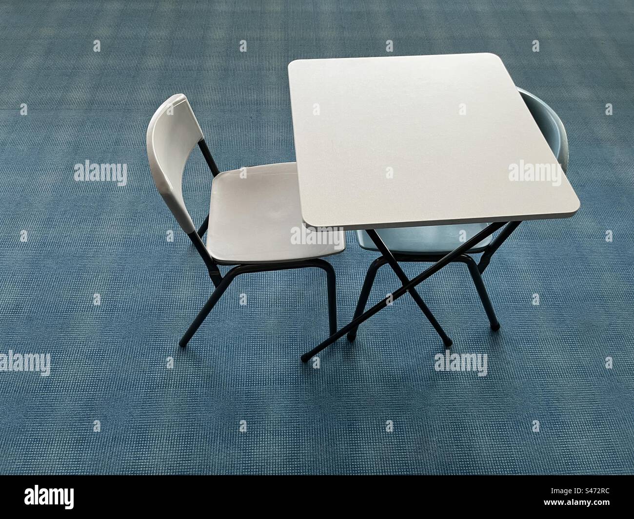 Tisch und zwei Stühle auf blauem Teppich Stockfoto