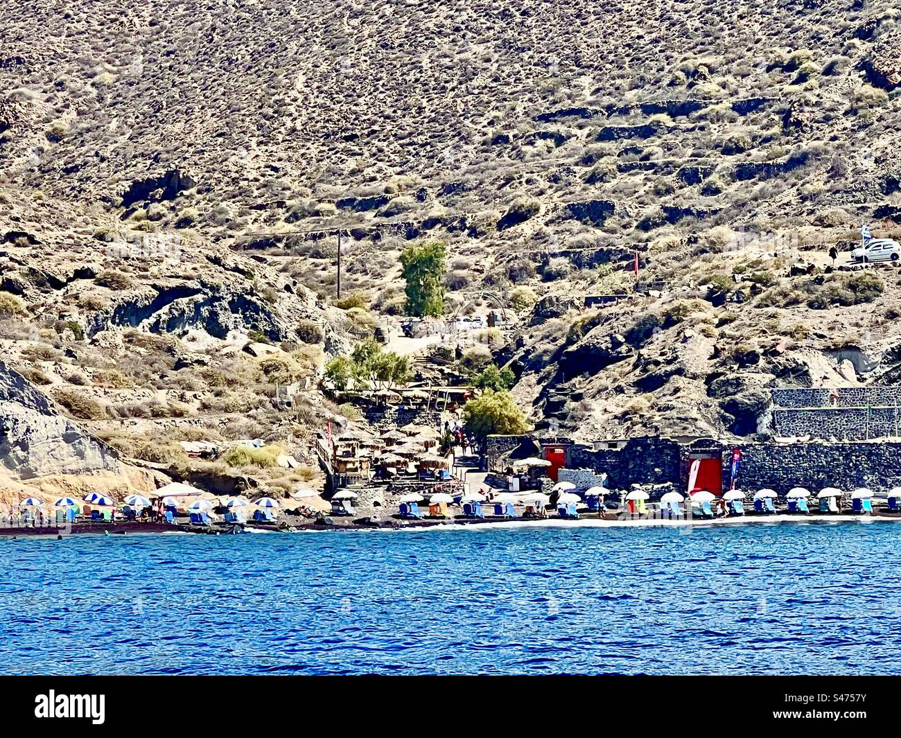 Reihen von Sonnenschirmen entlang Kaminia Beach, Santorin Stockfoto