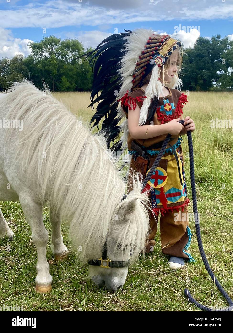 Ein Kind, das als Indianer mit seinem Shetland-Pony gekleidet ist Stockfoto