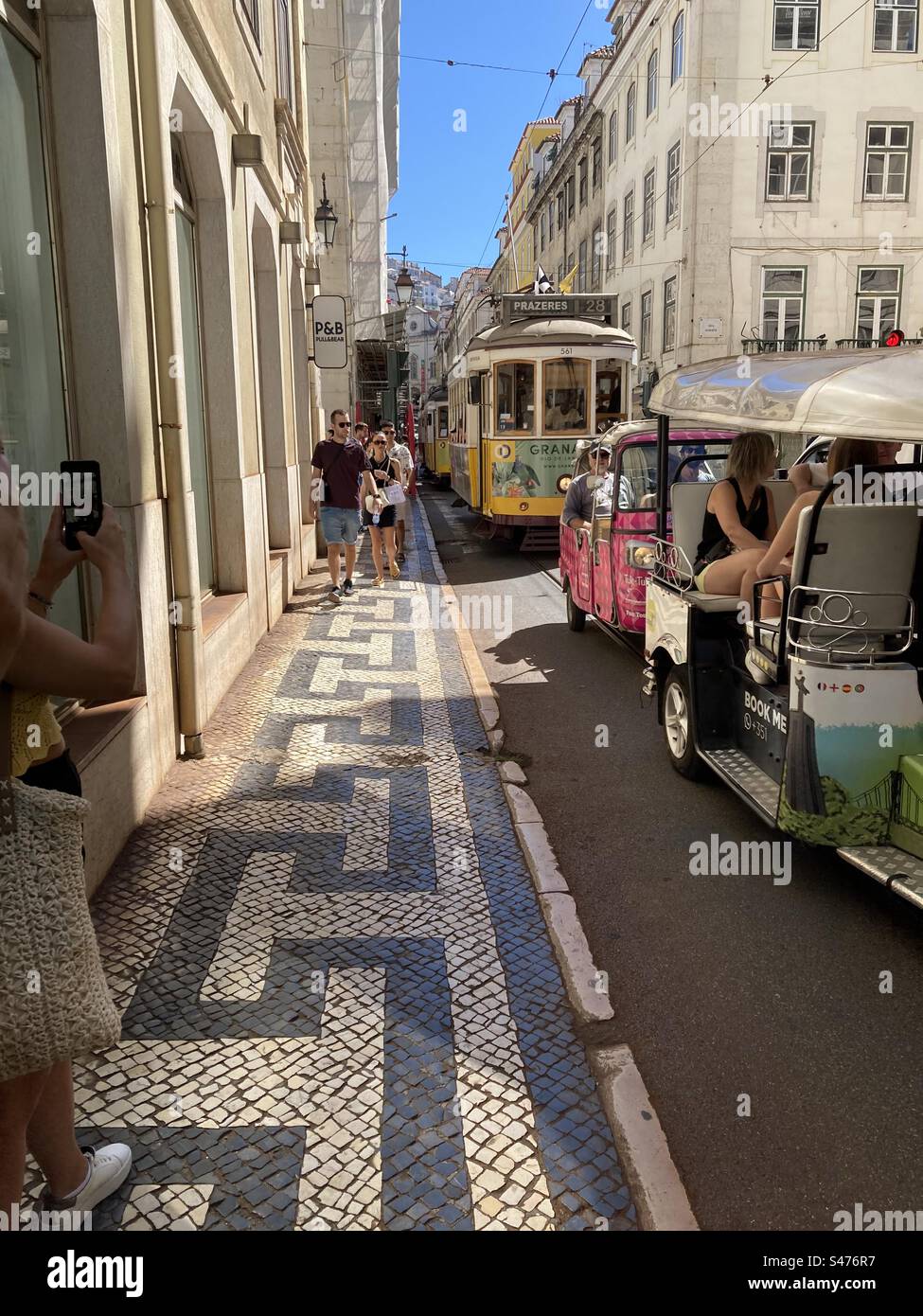 Typische Straße von Lissabon voller Touristen und Transport (elektrische Straßenbahn und die touristisch TucksTuks - große Trikes). Stockfoto