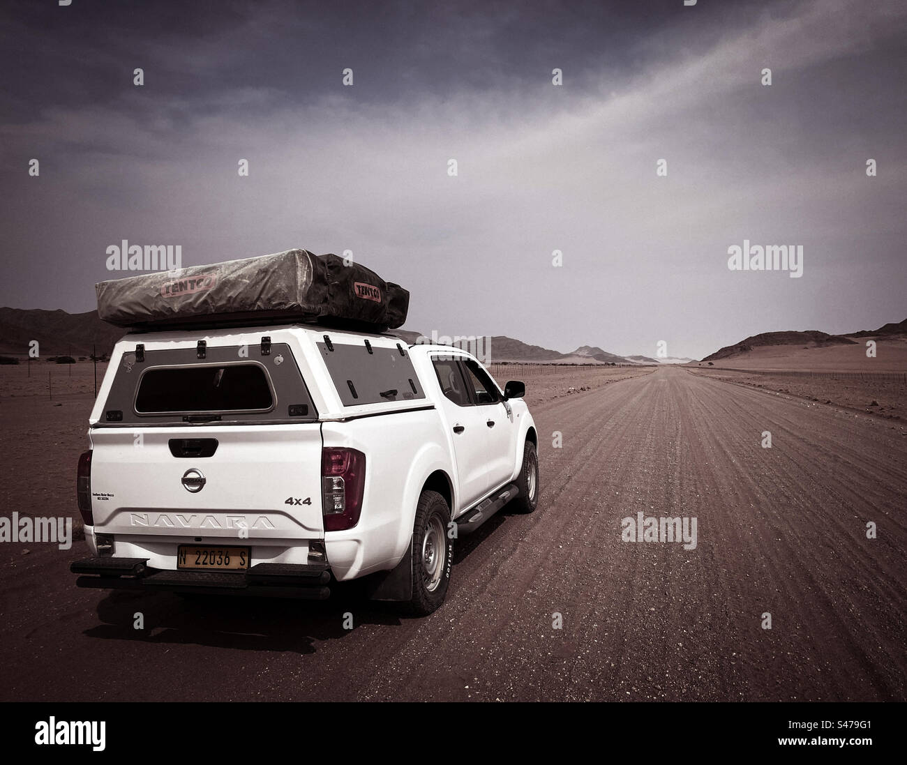 Ein weißer Geländewagen mit einem Dachzelt auf einer unbefestigten Straße in Namibia - Smartphone-aufgenommenes Stockfoto