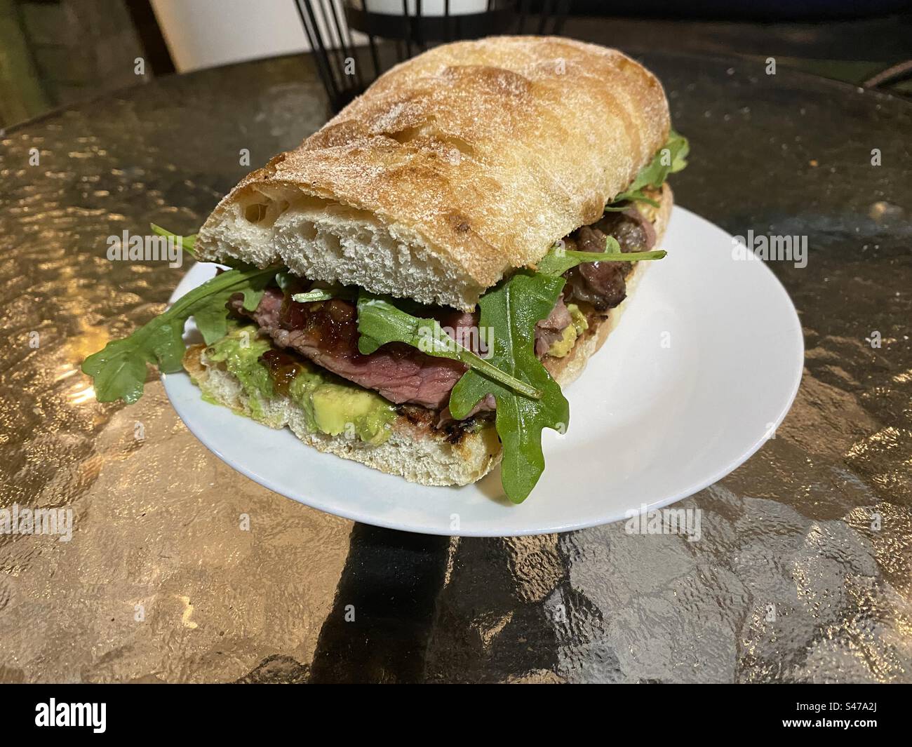 Steak-Sandwich mit Avocado, Speckmarmelade und Rakete. Stockfoto