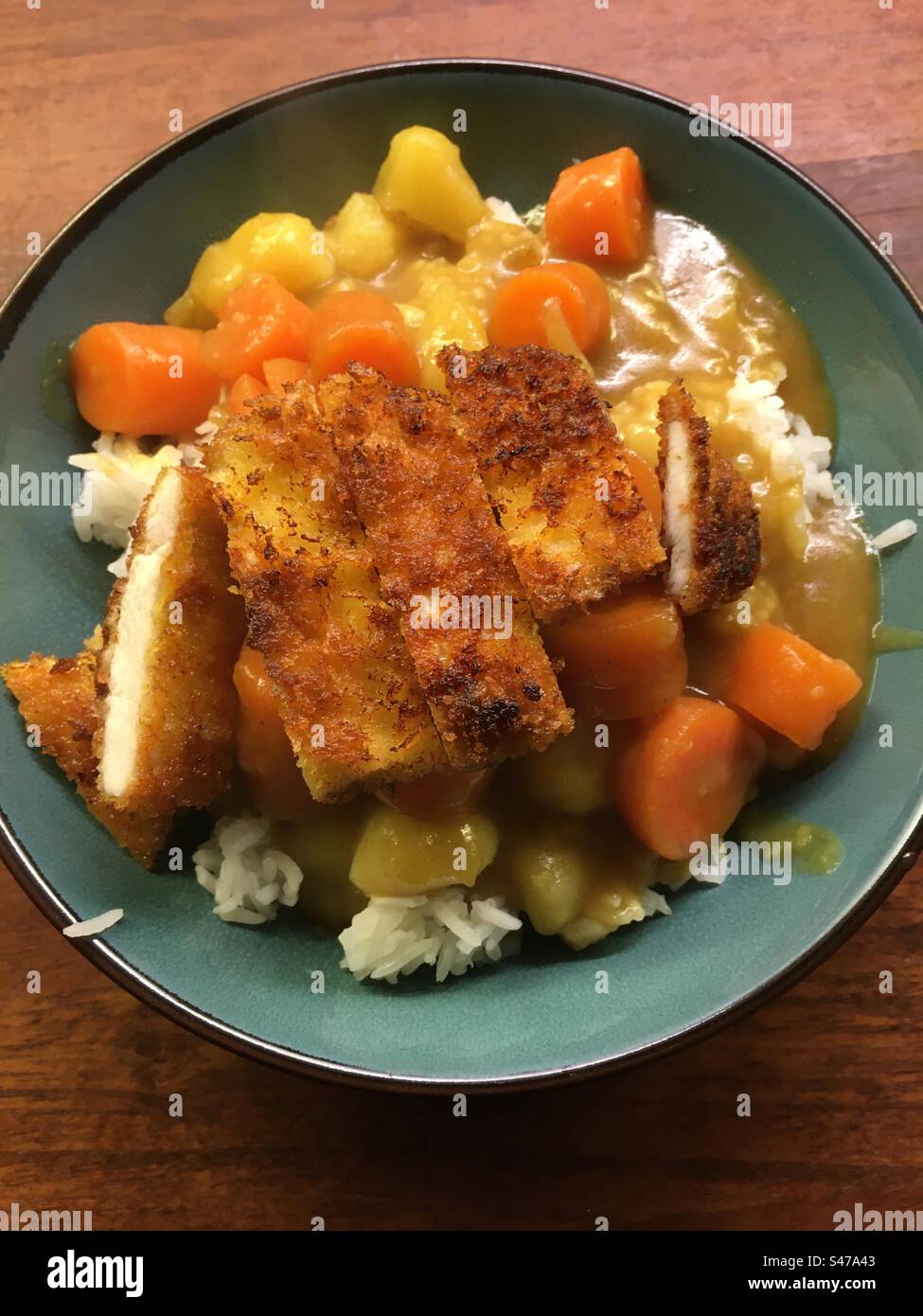 Hühnchen-katsu-Curry mit Reis in grüner Schüssel. Stockfoto