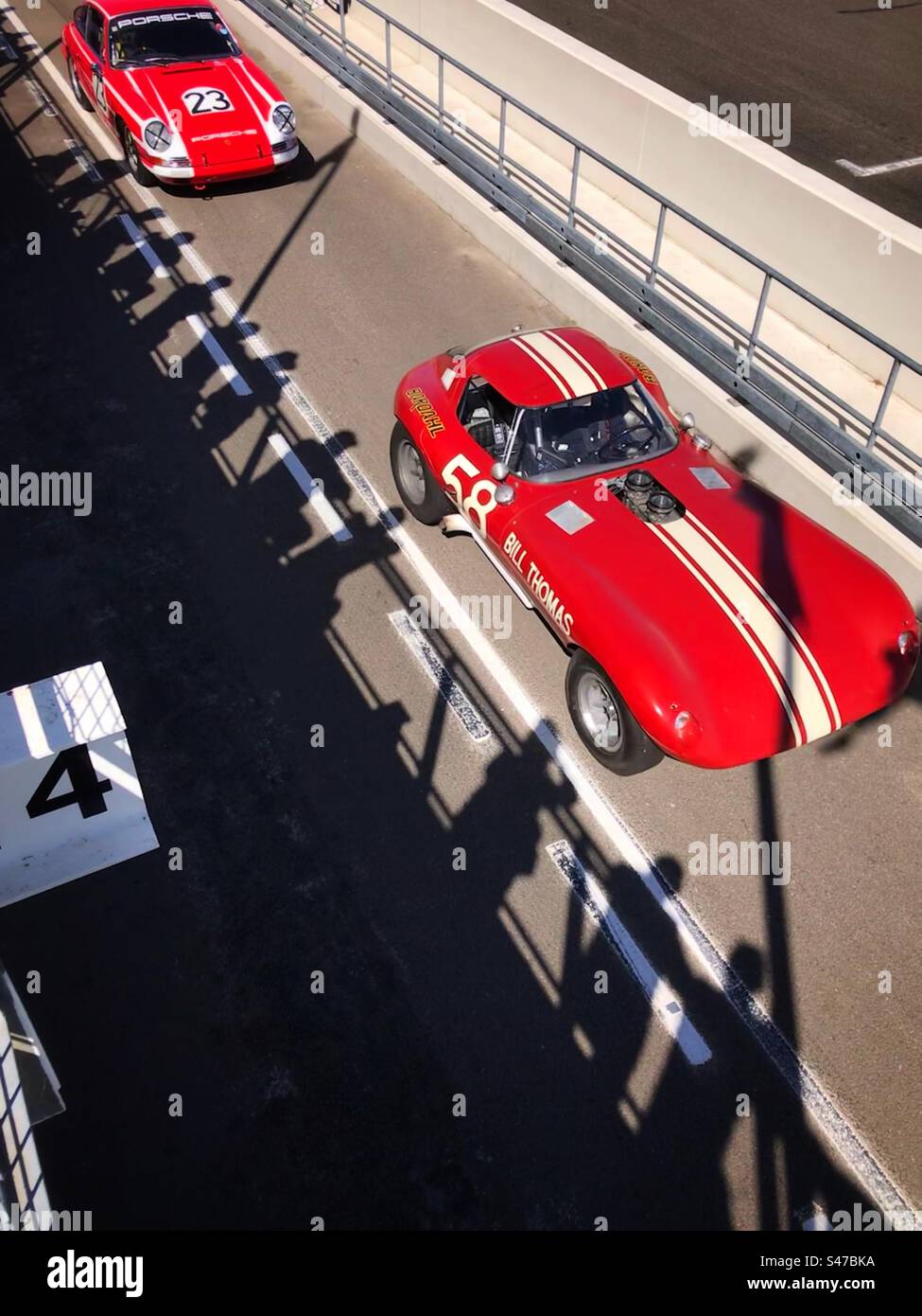 1960s Cobra & Porsche 911 in der Boxengasse auf Goodwood Motor Racing Circuit UK - Smartphone-aufgenommenes Stockfoto