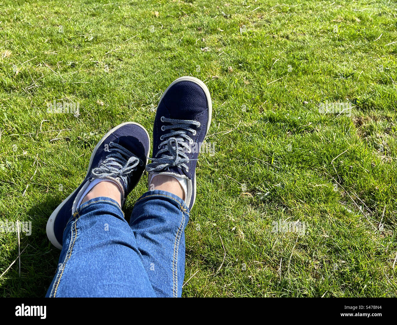 Überkreuzte Beine auf Gras. Stockfoto