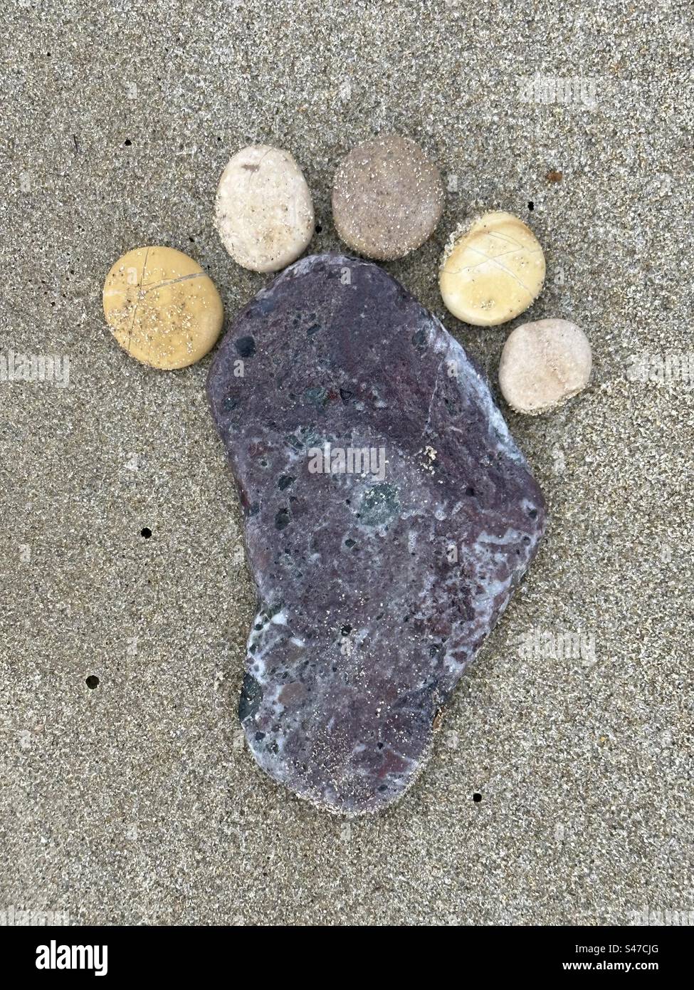 Erster Schritt, konzeptionelle kreative Komposition mit Steinen und Kieseln auf dem Sand Stockfoto