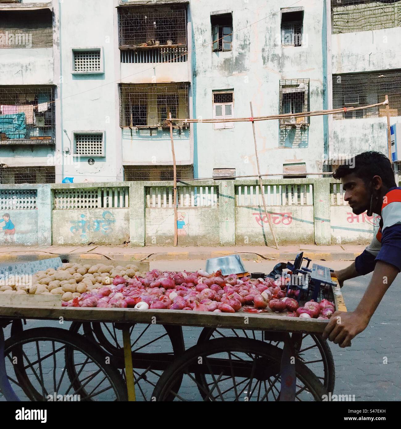 Ein Mann, der Zwiebeln und Kartoffeln auf einem Wagen in Indien verkauft - Smartphone-aufgenommenes Stockfoto