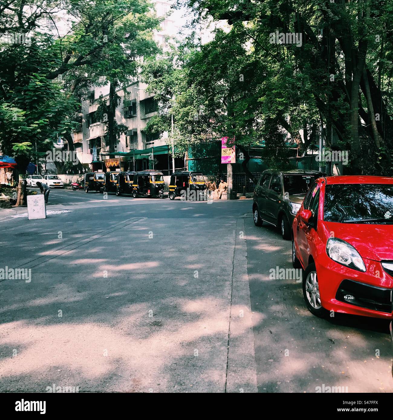Autos und Auto-Rikschas parken auf einer Straße in Mumbai, Indien - Smartphone-aufgenommenes Stockfoto