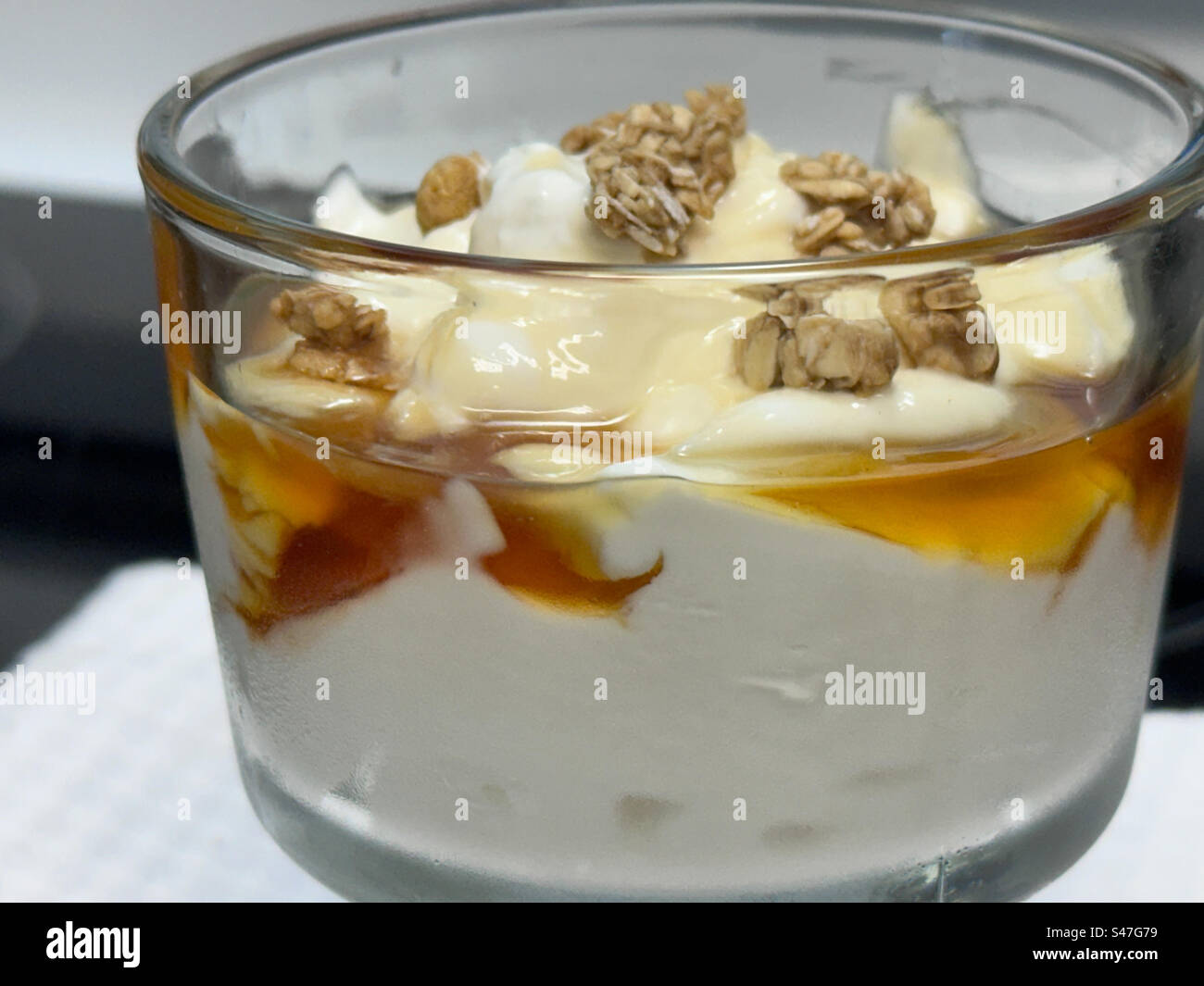 Fettarmer griechischer Joghurt mit Honig und Müsli in einer Glasschale. Stockfoto