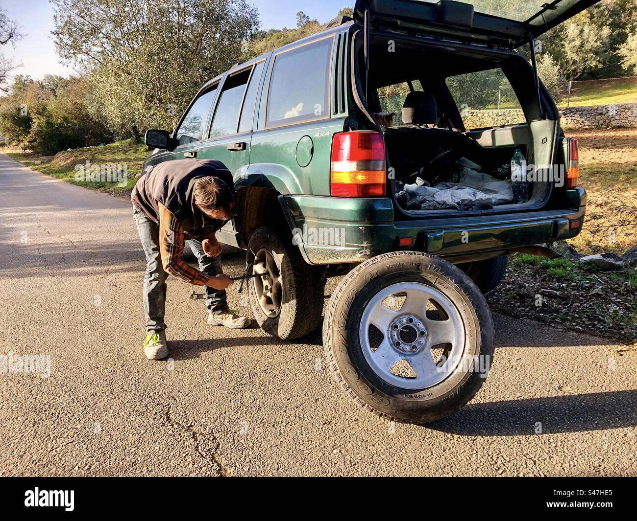 Mann, der einen Reifen in einem Jeep wechselt - Smartphone-aufgenommenes Stockfoto