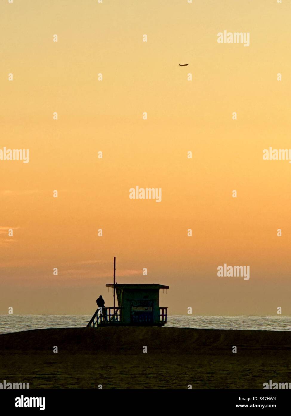 Lebensretter auf dem Turm am Strand in Los Angeles mit dem Jet, der im Hintergrund abfliegt. Stockfoto