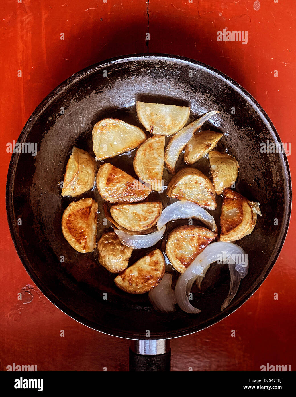 Gebratene Kartoffeln mit Zwiebeln in einem Topf auf einem roten Tisch in Queretaro, Mexiko Stockfoto