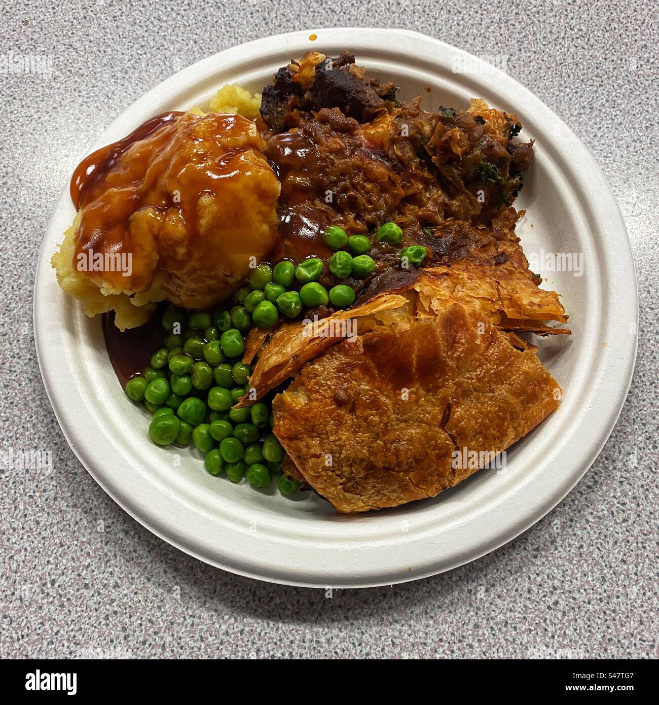 Rindfleisch und Ale Pie mit Kartoffelpüree, Erbsen und Soße. Winchester, Hampshire, England, Vereinigtes Königreich. - Smartphone-aufgenommenes Stockfoto