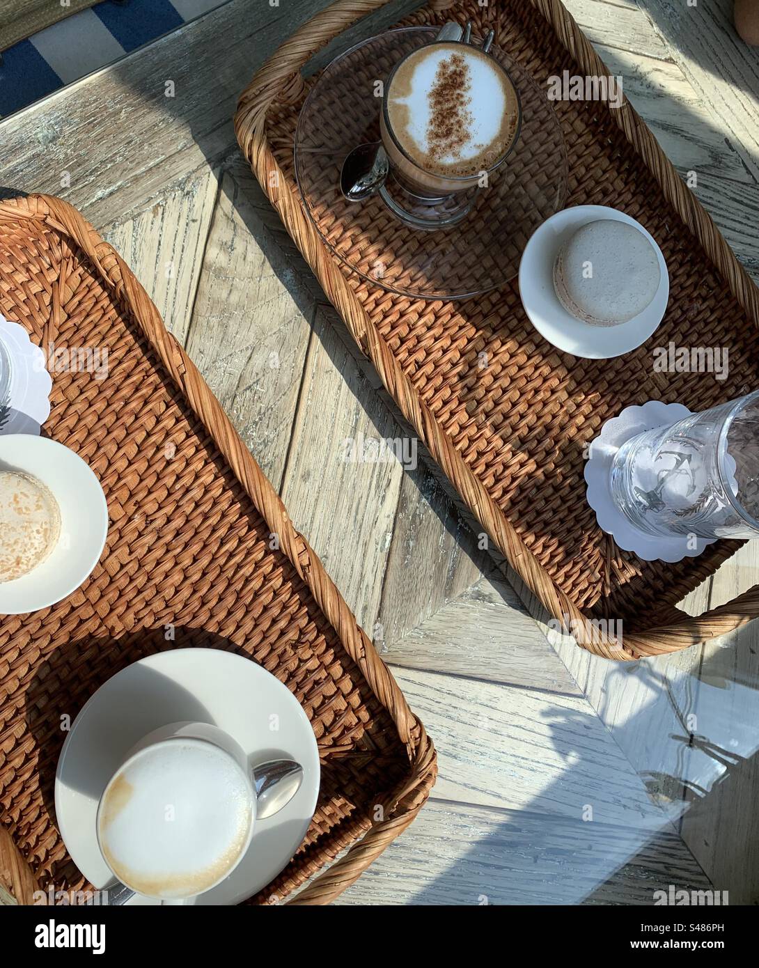 Kaffee und Makronen werden auf einem gewebten Korbtablett serviert - Smartphone-aufgenommenes Stockfoto