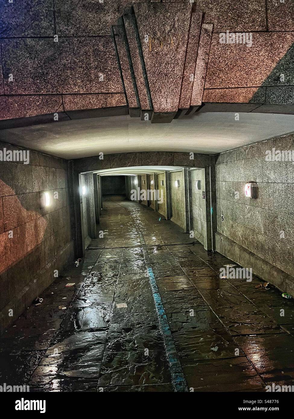 Unter der Westminster Bridge in London - der Tunnel verläuft unter der Straße - gesehen bei Nacht im Regen mit Reflexionen und Müll Stockfoto