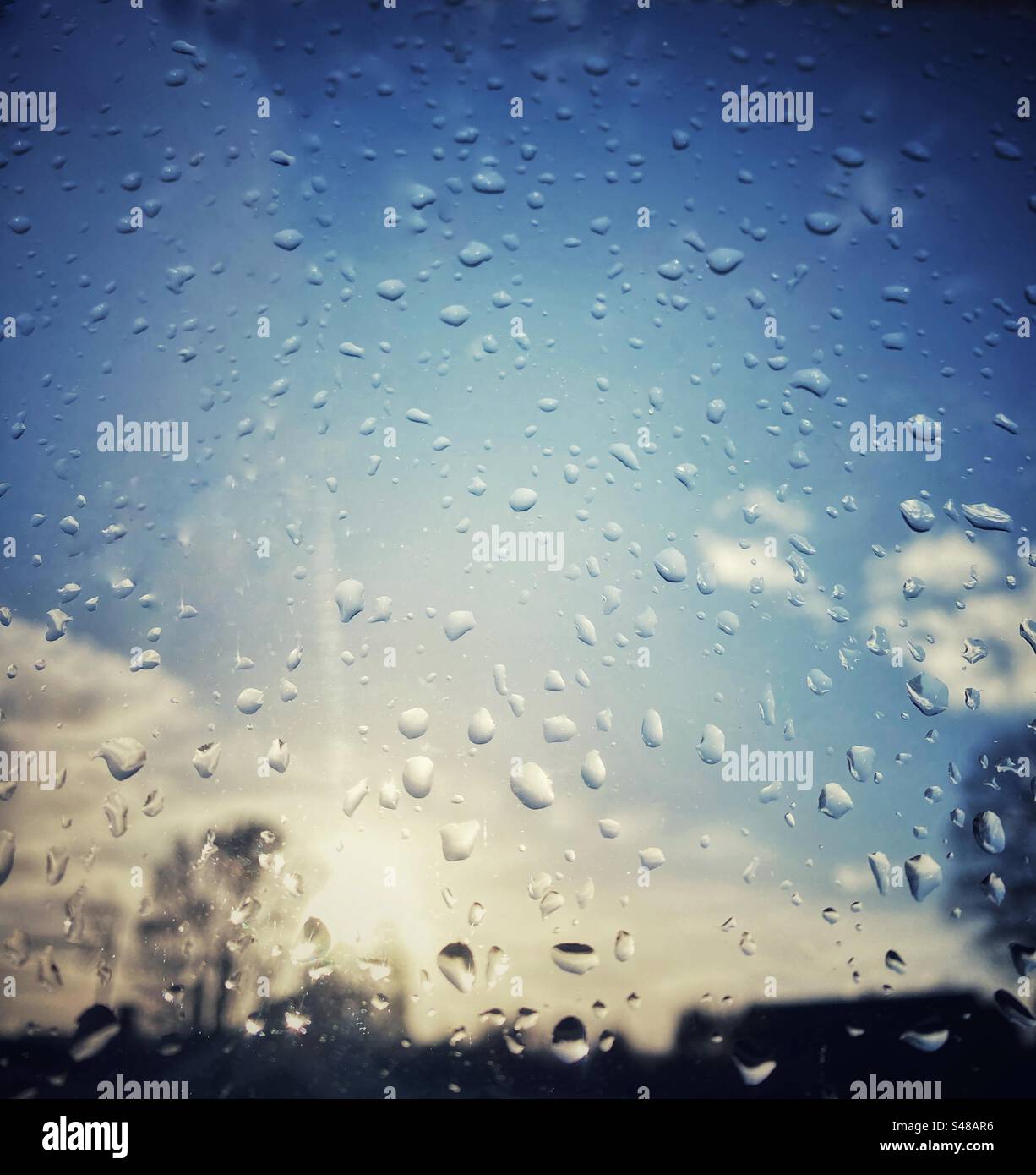 Ein Foto, das aus einem regnerischen Fenster auf den blauen Himmel blickt Stockfoto