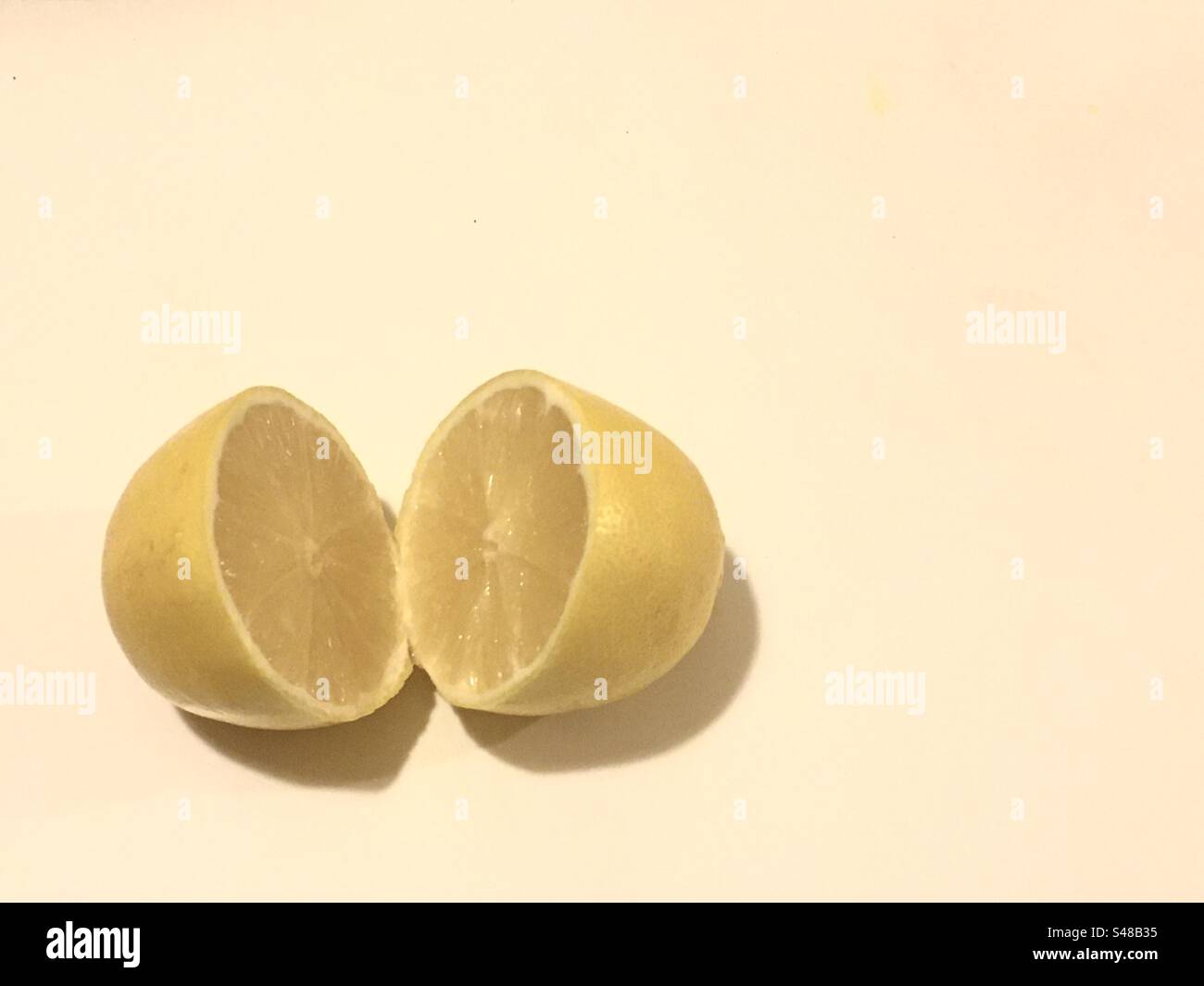 Zitrone in zwei Hälften auf hellem Hintergrund. Limone tagliato a metà su sfondo chiaro. - Smartphone-aufgenommenes Stockfoto
