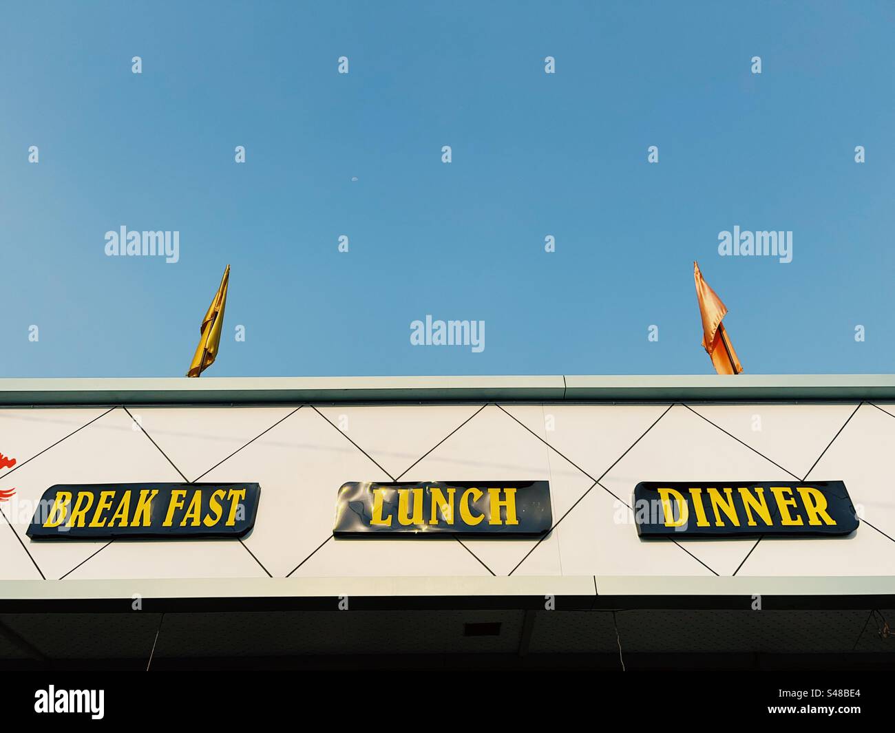 Restaurantttafel mit „Frühstück“, „Mittagessen“ und „Abendessen“ mit einem klaren blauen Himmel dahinter Stockfoto