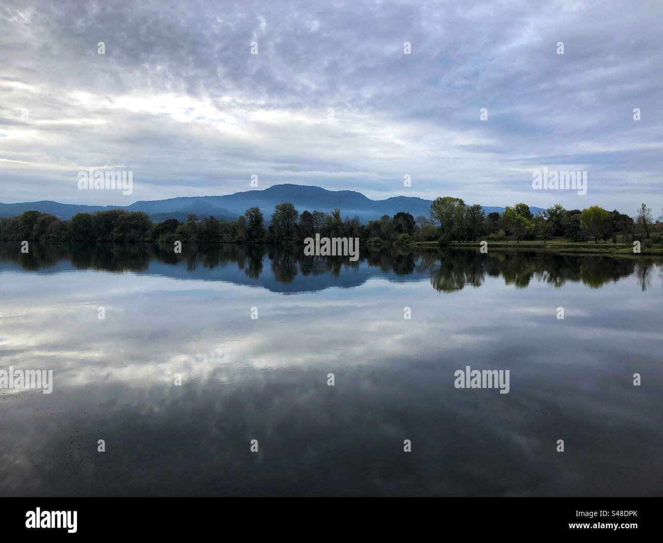 Valencia, Portugal - 22. Oktober 2023: Der Fluss Minho trennt Spanien von Portugal mit bewölktem Himmel, der sich im Wasser spiegelt - Smartphone-aufgenommenes Stockfoto