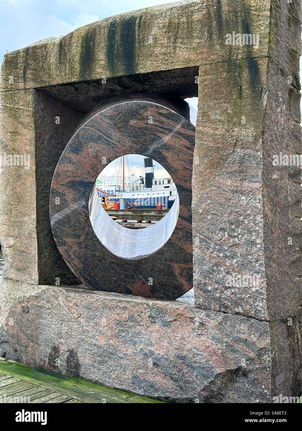 Ein Blick auf Schiffe im Hafen durch eine Skulptur von Pål Svensson in Eriksburg, Göteborg, Schweden. - Smartphone-aufgenommenes Stockfoto